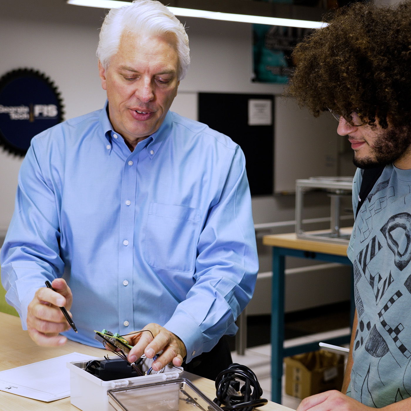 Professor showing a student a circuit board.